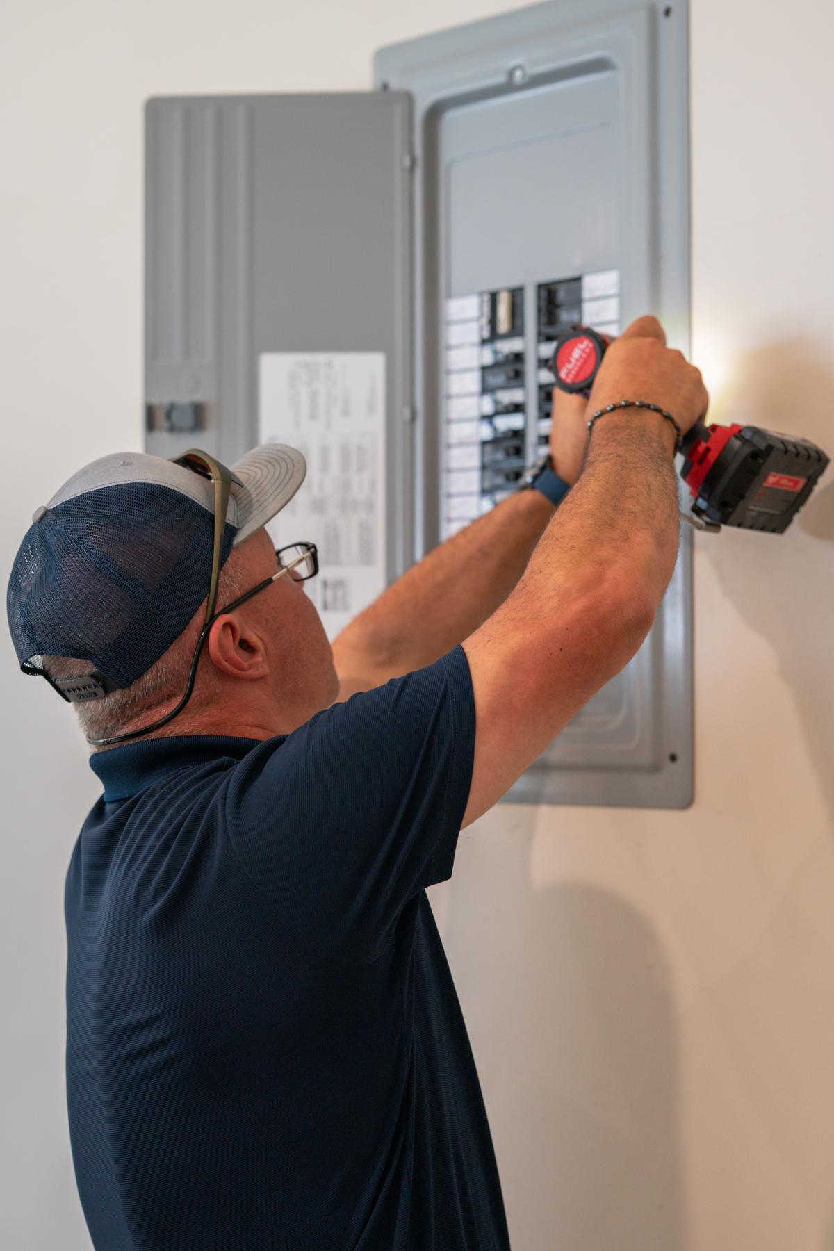 Inspector removing an electrical panel cover to inspect breakers and wiring