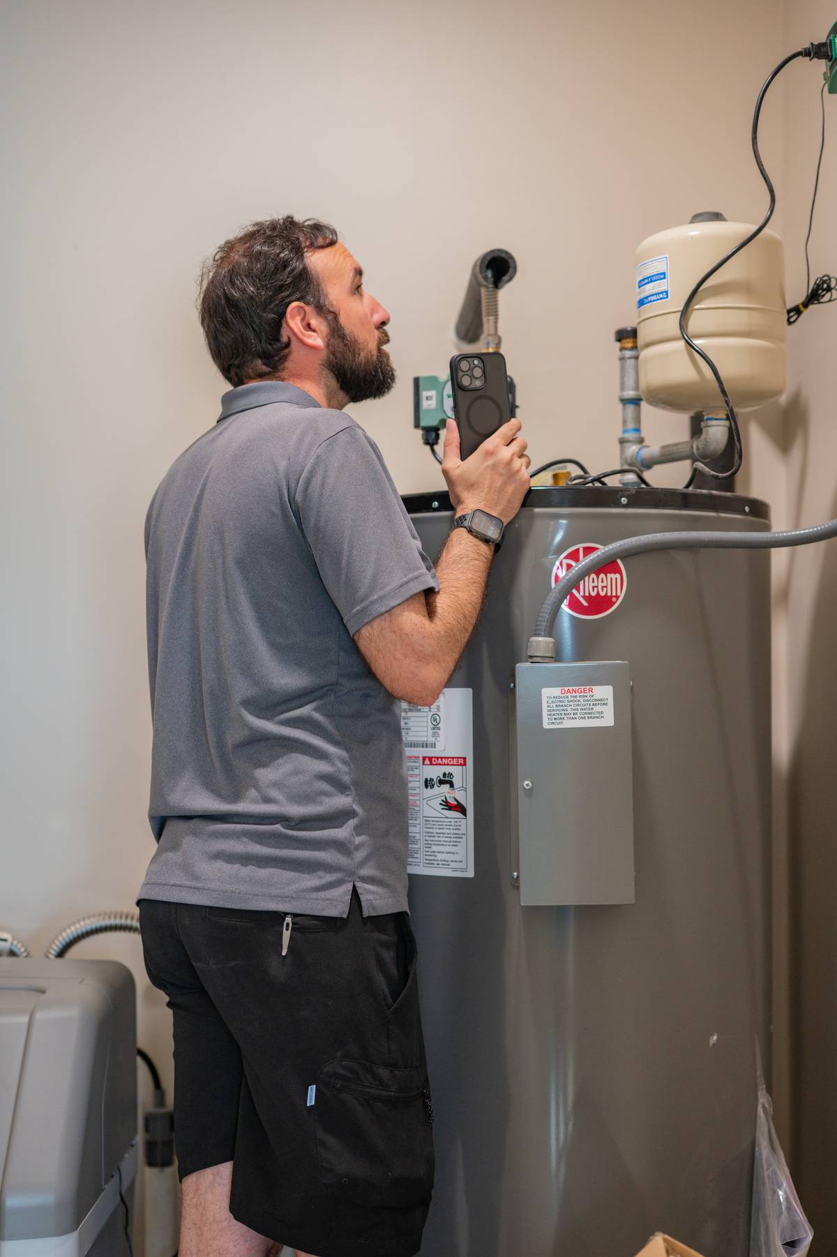 Inspector documenting a water heater and its connections during a home inspection